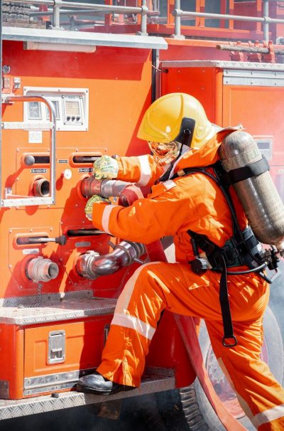 Firefighter man wearing protective fire suite and helmet with water car truck equipment and accessor